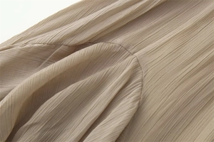 Vue détaillée de la texture du tissu en mousseline plissée beige clair et des coutures