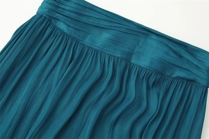 Detail of teal pleated satin skirt showing elegant horizontal and vertical folds