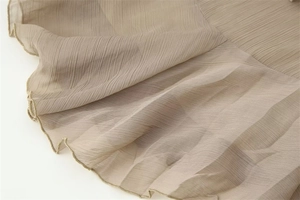Gros plan sur le tissu plissé marron clair avec des bords ondulés finition laitue