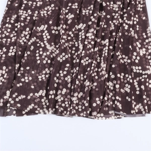 Detail of sheer brown pleated mesh fabric with white polka dot gradient pattern