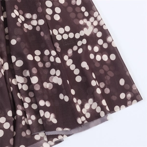 Detail of sheer dark brown mesh fabric with white polka dots and delicate hem stitching
