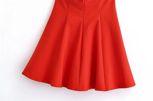 Close-up of the red A-line dress hem featuring elegant pleated details and structured fabric