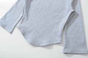Detail of the curved hem and lettuce edge stitching on a grey knit boat neck top