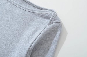 Detailed macro view of light grey boat neck knit top showing precise shoulder stitching