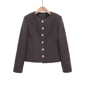 Detailed view of dark grey tweed jacket featuring textured fabric and gold embossed buttons