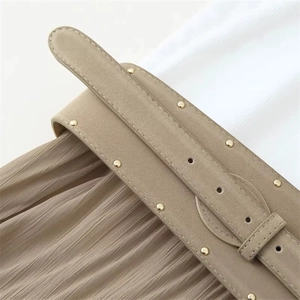 Large ceinture femme en daim kaki avec rivets dorés sur une jupe plissée