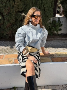 Detail of light blue high-neck jacket and zebra print skirt with fashion accessories