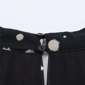 Detailed back neckline of a black polka dot dress featuring keyhole cutout and two buttons
