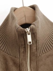 Detailed macro view of the ribbed knit stand collar and gold metal zipper on a brown jacket