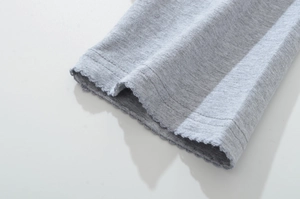 Detail of light grey knit fabric with curly lettuce hem and double-row stitching detail