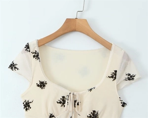 Close-up of floral print dress detail with drawstring neckline and cream fabric