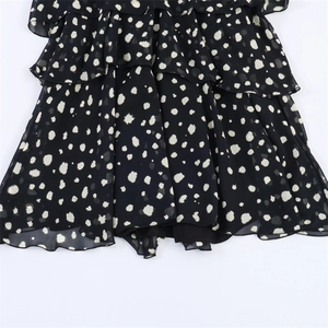 Close-up of tiered ruffle hem on a black polka dot dress with layered light fabric