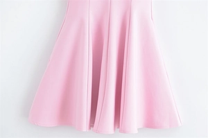 Detail of pink A-line dress hem showing elegant pleats and smooth fabric texture