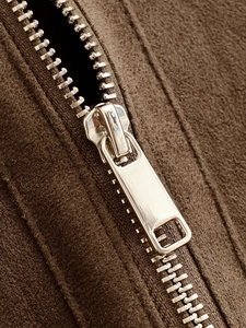 Detail of silver metal zipper and soft brown suede texture on a women's ribbed jacket