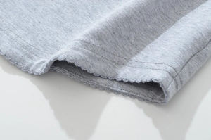 Macro detail of grey knit fabric with decorative wavy edge stitching on boat neck top