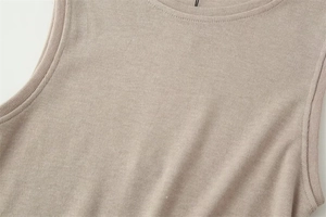 Close-up of the fine knitted texture and armhole stitching on a beige sleeveless top