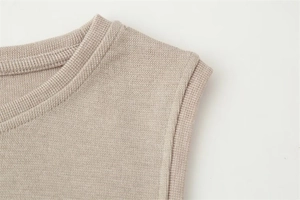 Detailed close-up of ribbed neckline and fine knit texture on a beige sleeveless top