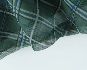 Détail du tissu en maille à carreaux verts avec coutures fines et texture voile