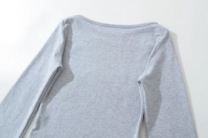 Detail of light grey boat neck knit top showing fine fabric texture and neckline finish
