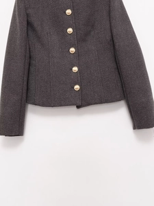 Close-up of golden embossed buttons on a dark grey tweed blazer jacket detail