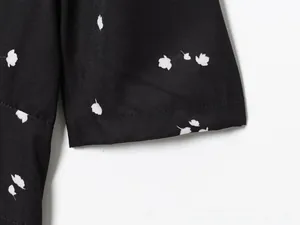 Detail of puff sleeve cuff with delicate floral print and precise stitching on black dress