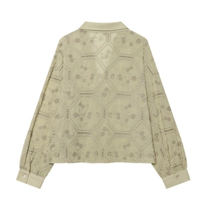 Macro detail of geometric eyelet embroidery and floral patterns on green cotton shirt