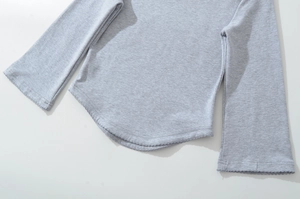 Detailed macro view of light gray knit top featuring curved hem and decorative stitching