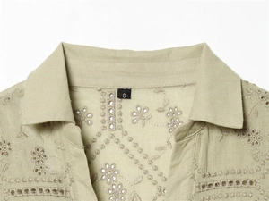 Detail of delicate broderie anglaise embroidery on the collar of a sage green cotton shirt