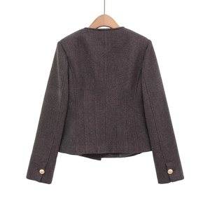 Detail view of the back of a dark charcoal tweed jacket with gold button sleeve accents