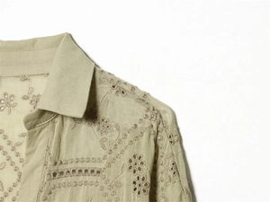 Detail of delicate floral embroidery and broderie anglaise on a soft green cotton shirt
