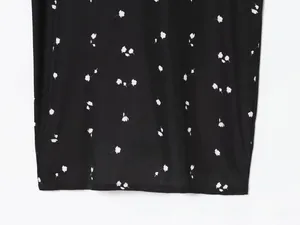 Detail of black floral dress fabric showing white micro flower pattern and smooth texture