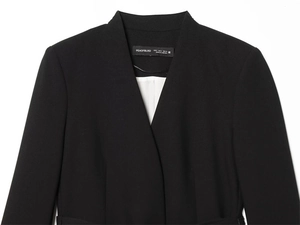 Détail d'un blazer noir sans col à col en V montrant l'étiquette S et le tissu en sergé