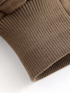 Detailed macro view of dark brown ribbed knit cuffs and faux suede fabric on jacket