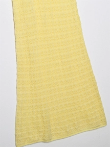 Detailed view of yellow pointelle knit fabric with intricate geometric hollow patterns