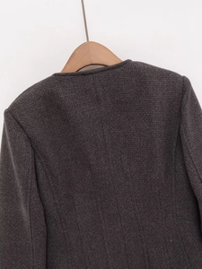 Detail of dark grey textured tweed jacket with round neck and neat stitching on back