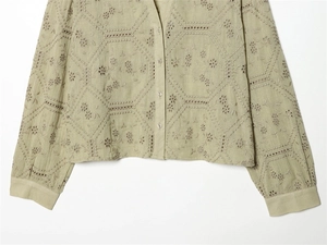 Detailed view of sage green shirt featuring intricate floral embroidery and cut-out texture