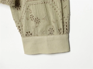 Close-up of sage green blouse cuff featuring intricate broderie anglaise embroidery detail