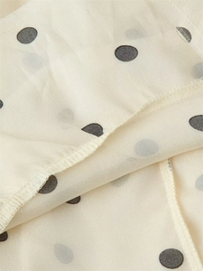 Vue macro détaillée d'un tissu mousseline léger à pois noirs avec des coutures de haute qualité