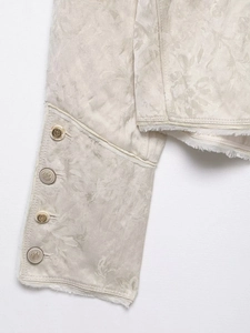 Detailed macro view of cream jacquard sleeve with four vintage gold crest buttons