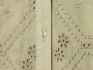 Close-up of light green shirt with white floral embroidery and pearl button detail