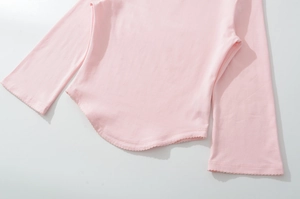 Detail of pink knitted top featuring a curved hem and delicate scalloped edge finish