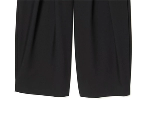Détail du pantalon large noir montrant des plis élégants et un tissu drapé de haute qualité