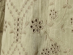 Close-up of olive green Broderie Anglaise embroidery on breathable cotton linen fabric
