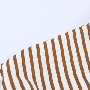 Close-up of brown and white striped fabric with vertical ribbed texture for jumpsuit
