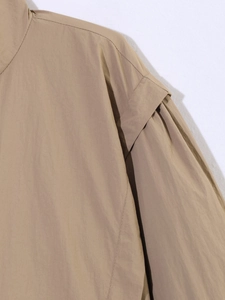 Close-up of khaki jacket shoulder with layered seams and ripstop fabric texture