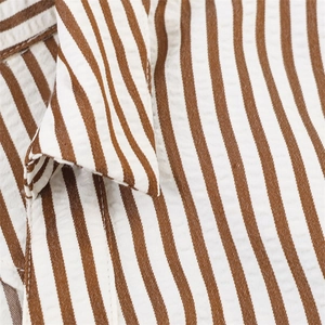 Macro detail of brown and white striped seersucker fabric texture with neat stitching