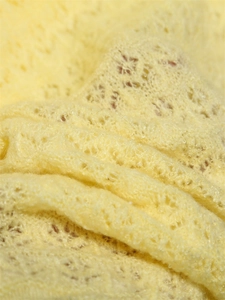 Detailed macro view of the light yellow hollow out crochet knit pattern and soft texture