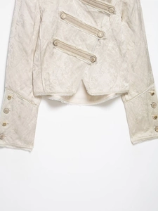 Detailed macro view of cream jacquard fabric with raw edge texture and gold crest buttons