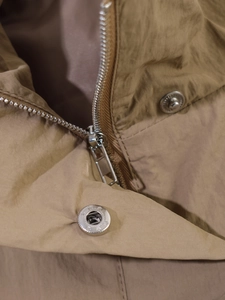 Close-up of silver metal zipper and snap buttons on a khaki windbreaker jacket