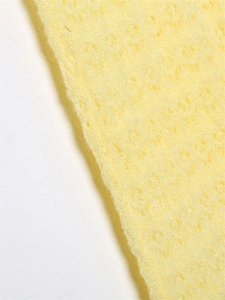 Macro shot of bright yellow high-density foam texture with uniform porous structure